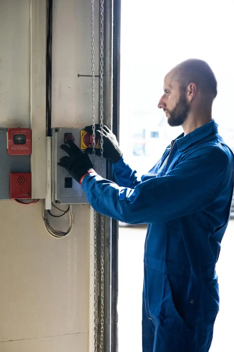 A technician in blue overalls operates a control switch inside a facility, focused and attentive.